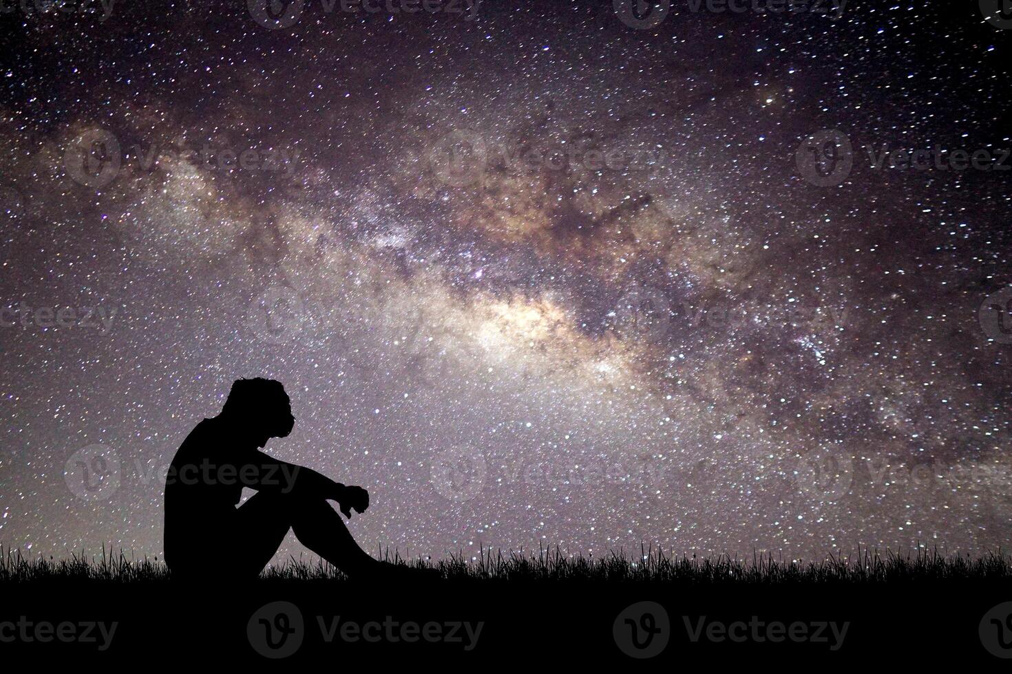 Silhouette of a Person Sitting Under a Starry Night Sky with the Milky Way in the Background photo