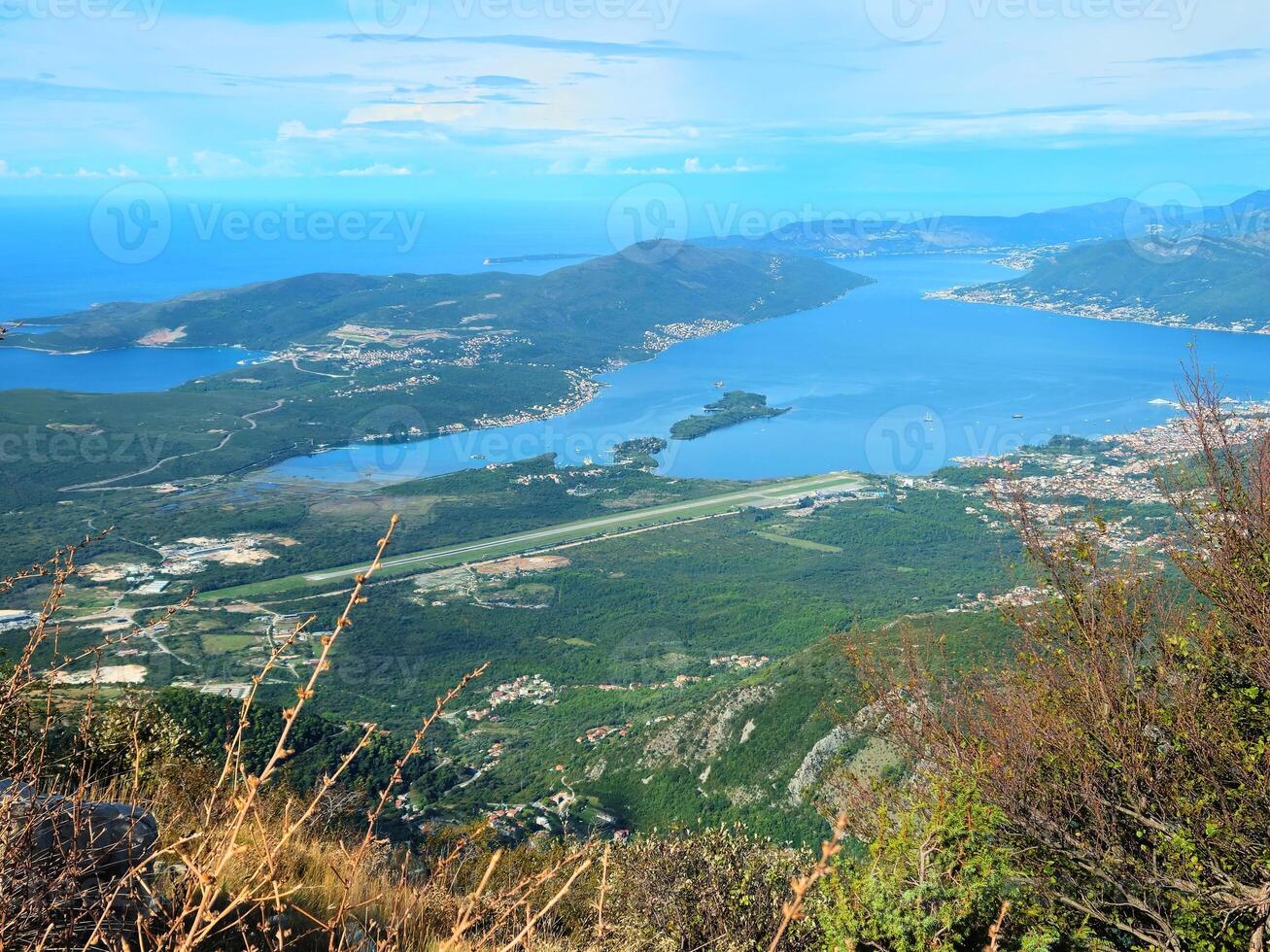 Horizontal aerial view of Tivat Airport and the Bay of Kotor, Montenegro, with surrounding coastline, mountains, and blue sky with copy space. Perfect for travel brochures or tourism promotions. photo