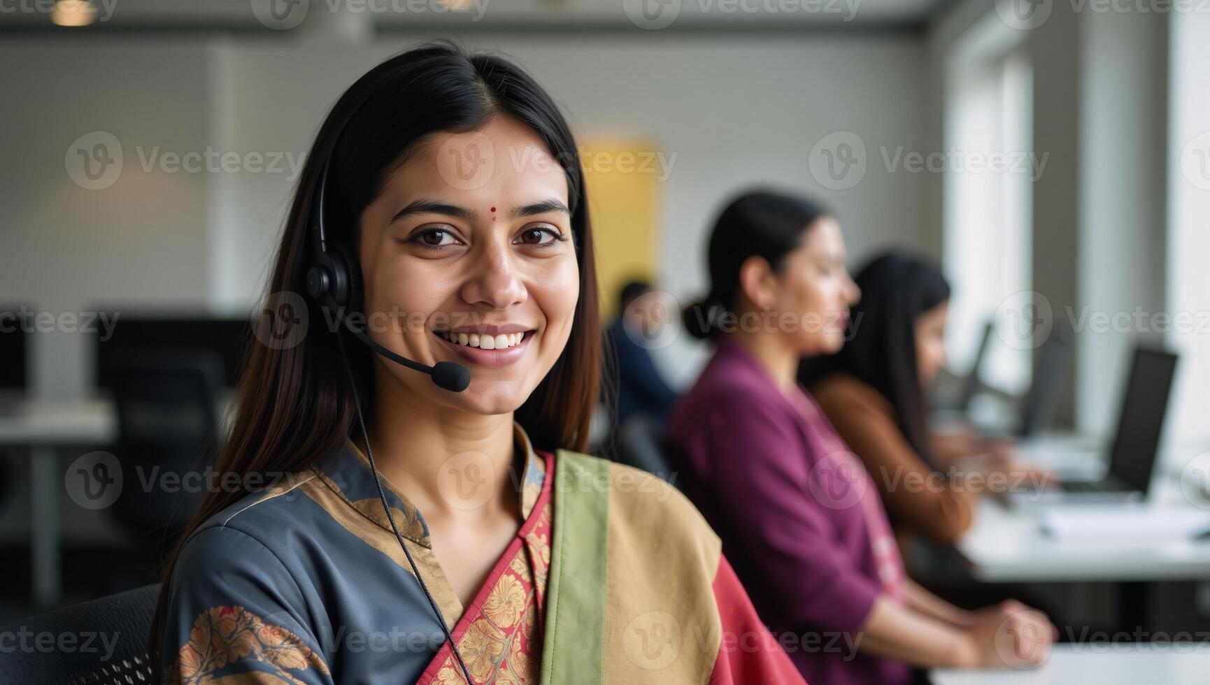 Closeup portrait of an Indian customer service representative wearing a headset at their desk to represent the concept of support services photo