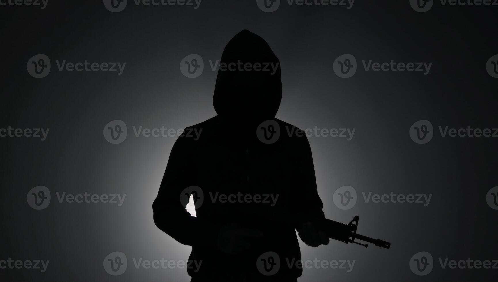 Silhouette of a hooded figure with a gun exuding mystery and danger photo