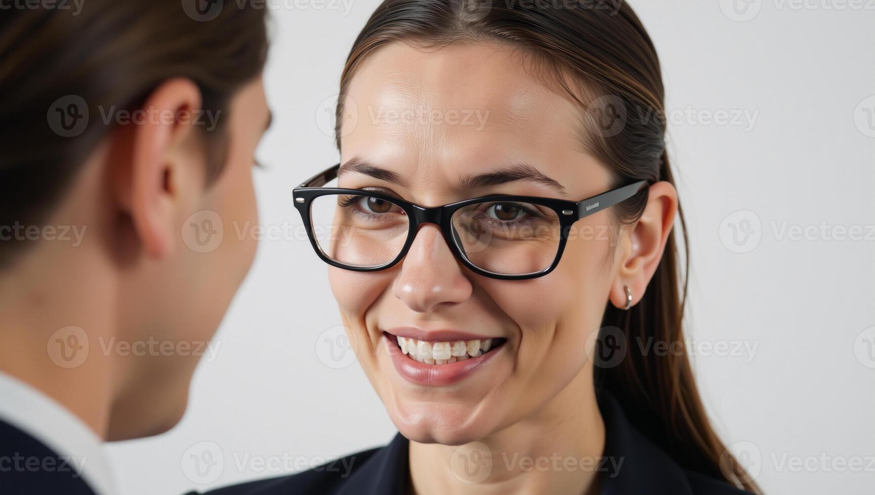 Businesswoman sharing strategy ideas with mentor sporting black glasses and silver earring displaying an animated expression through an open mouth large nose and striking combination of brown and blue photo
