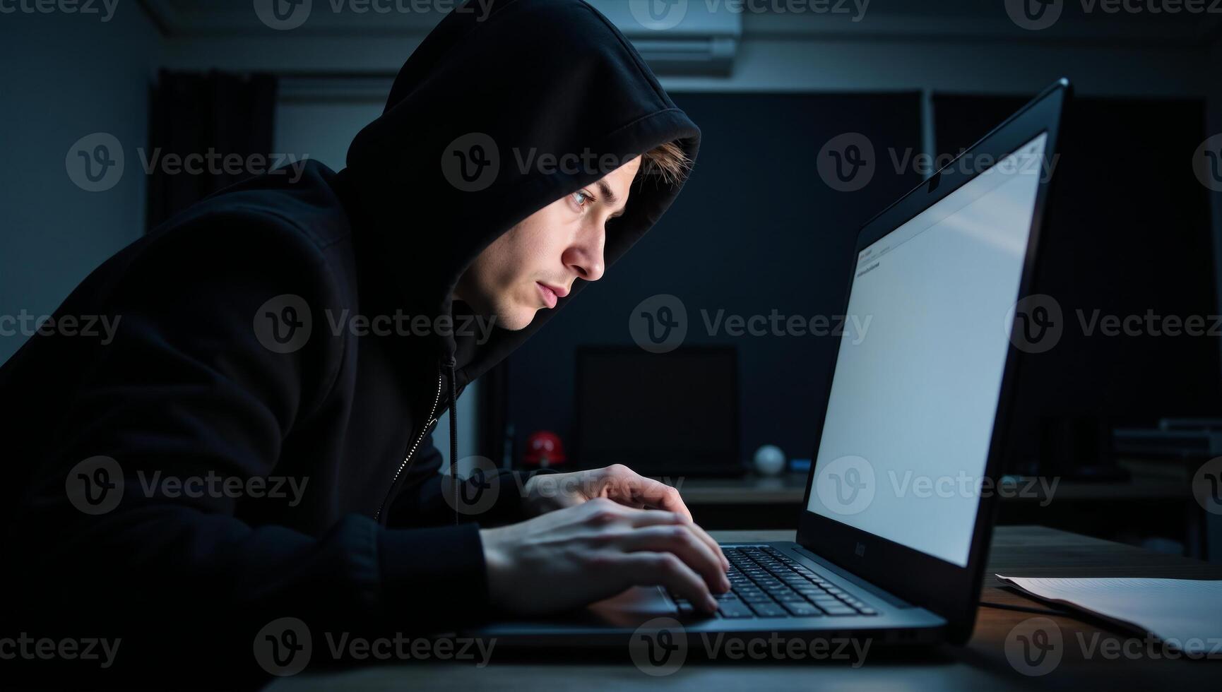 A criminal hacker at work on his laptop ready to commit a cybercrime photo