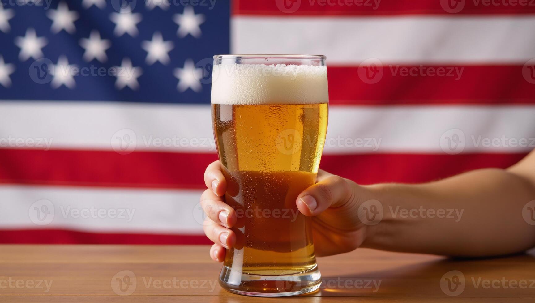 Hand holds frothy beer over blurred American flag patriotic celebration theme photo
