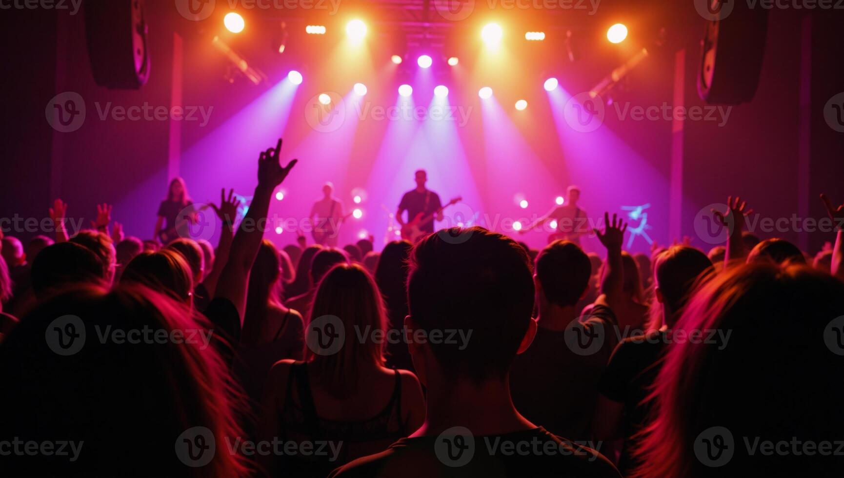 A lively concert scene featuring an enthusiastic crowd raising their arms amidst vibrant stage lighting as the band performs live photo