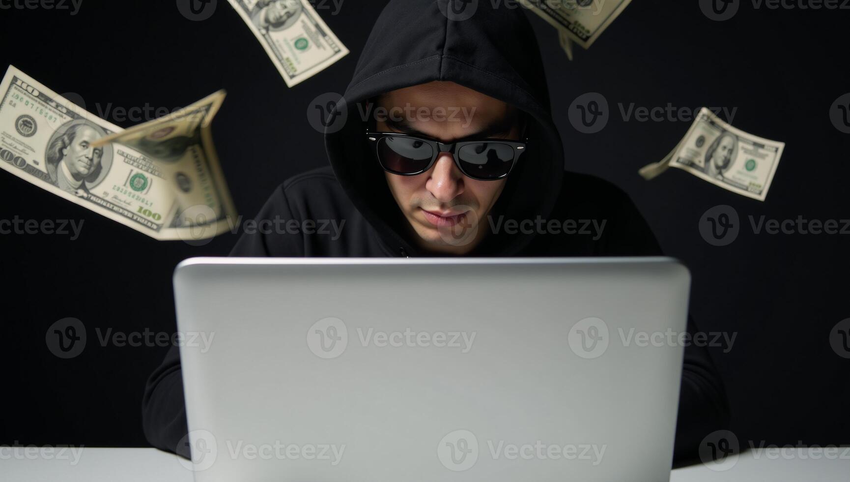 Hooded hacker with sunglasses and laptop amidst cascading dollar bills represents cyber crime online fraud and data theft photo
