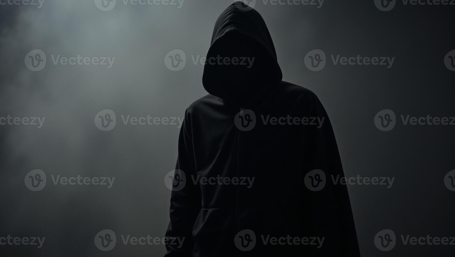 Hooded figure with gun in dark silhouette photo