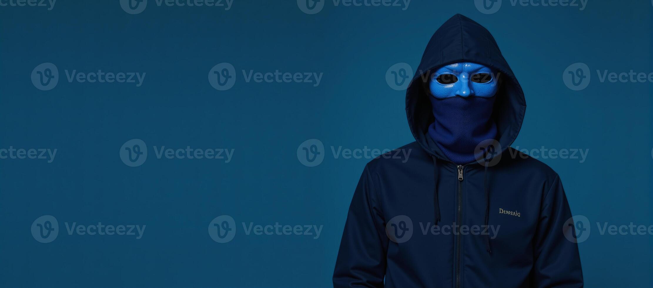 Bluemasked veiled individual with hood on blue studio backdrop photo