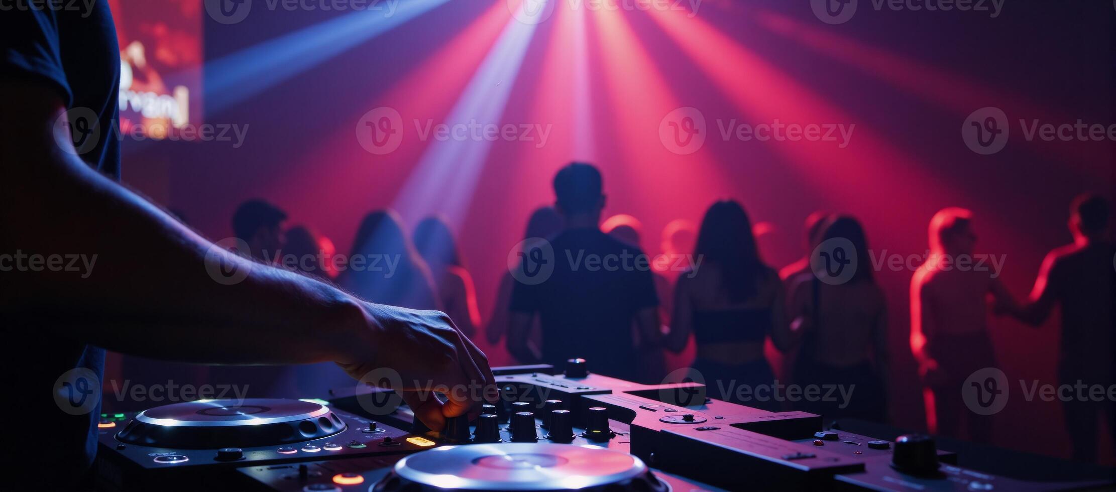 A DJ mixes tracks against pulsing strobe lights amidst a lively club setting photo