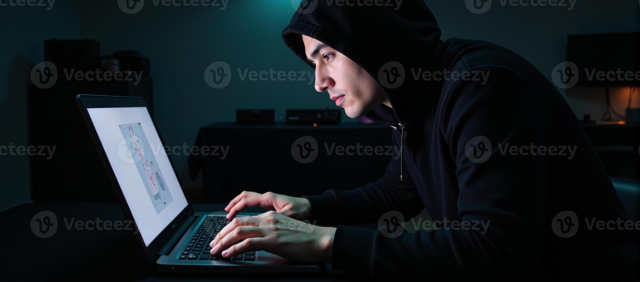 A criminal hacker at work on his laptop ready to commit a cybercrime photo
