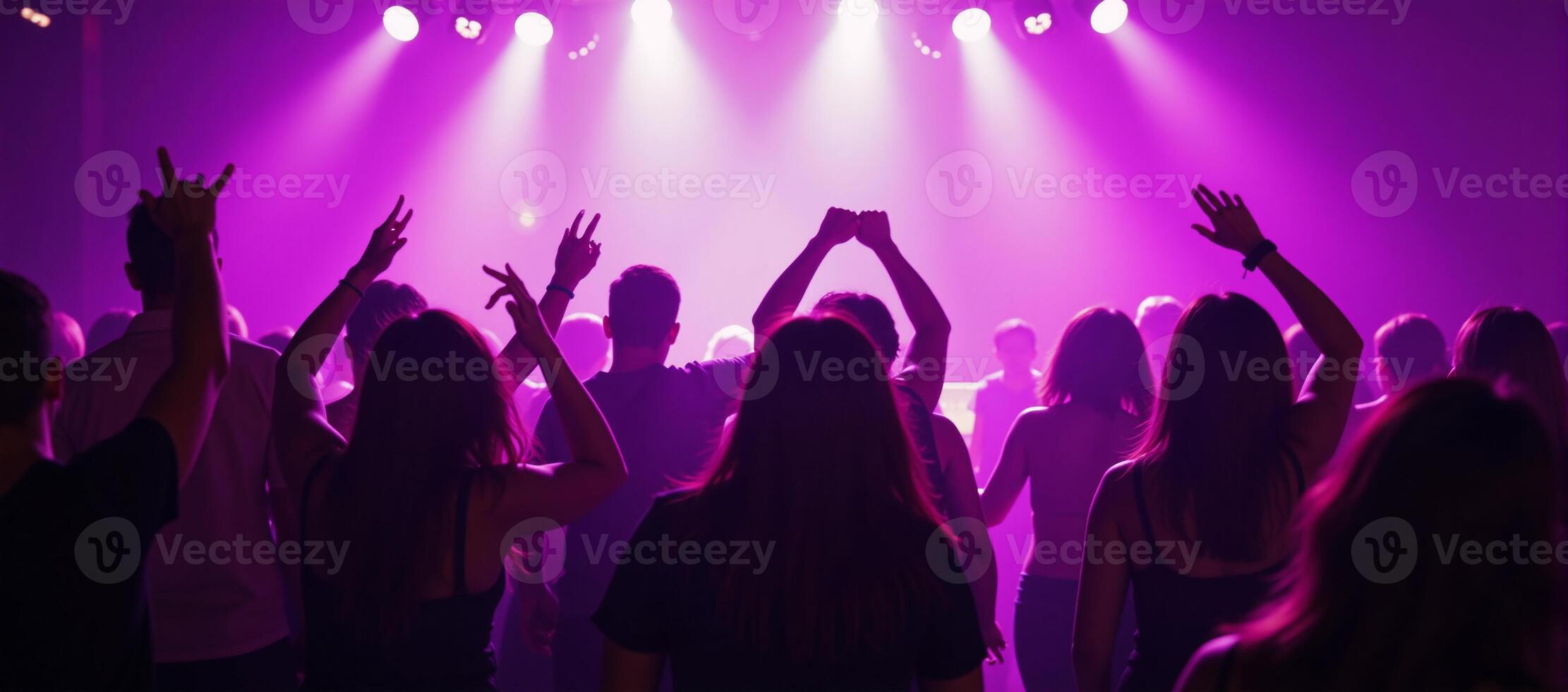Vibrant nightlife dancing crowd in a purplishpinklit club scene with youthful energy and movement on the dancefloor photo