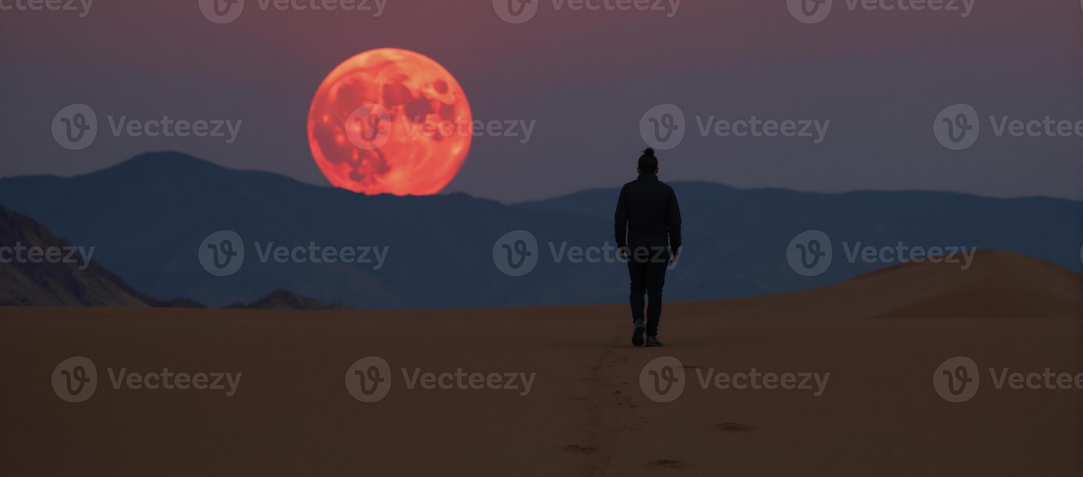 A solitary character traverses a barren desert under a bloodred moon photo