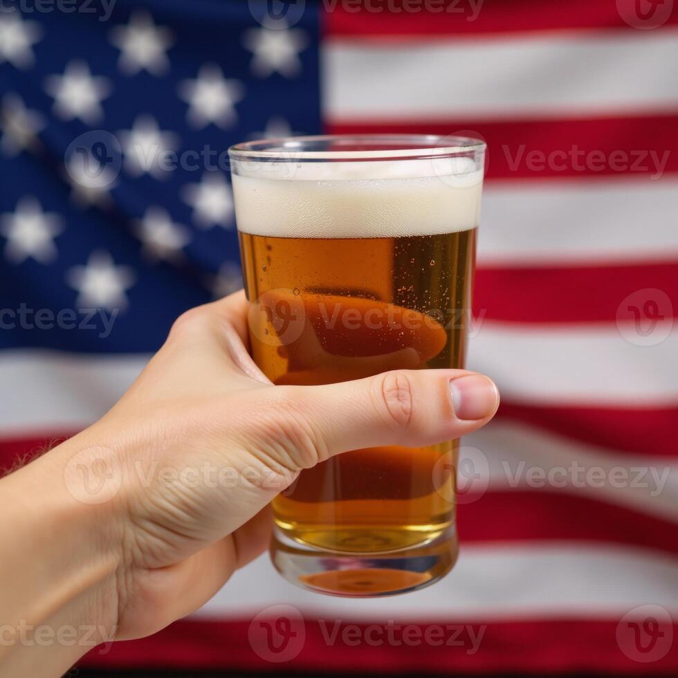 Hand holds frothy beer over blurred American flag patriotic celebration theme photo