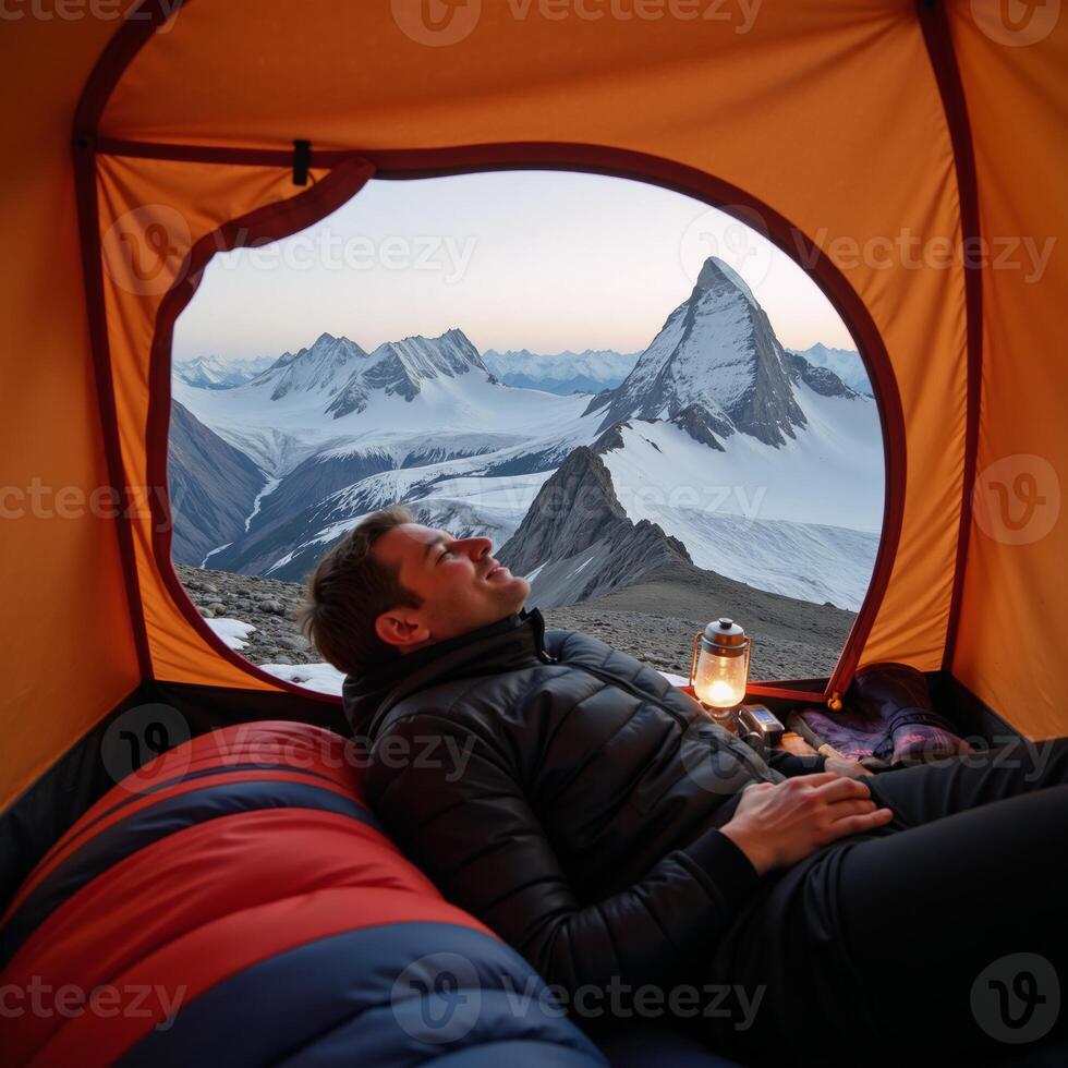 Hiker camping in a tent on a mountain peak photo