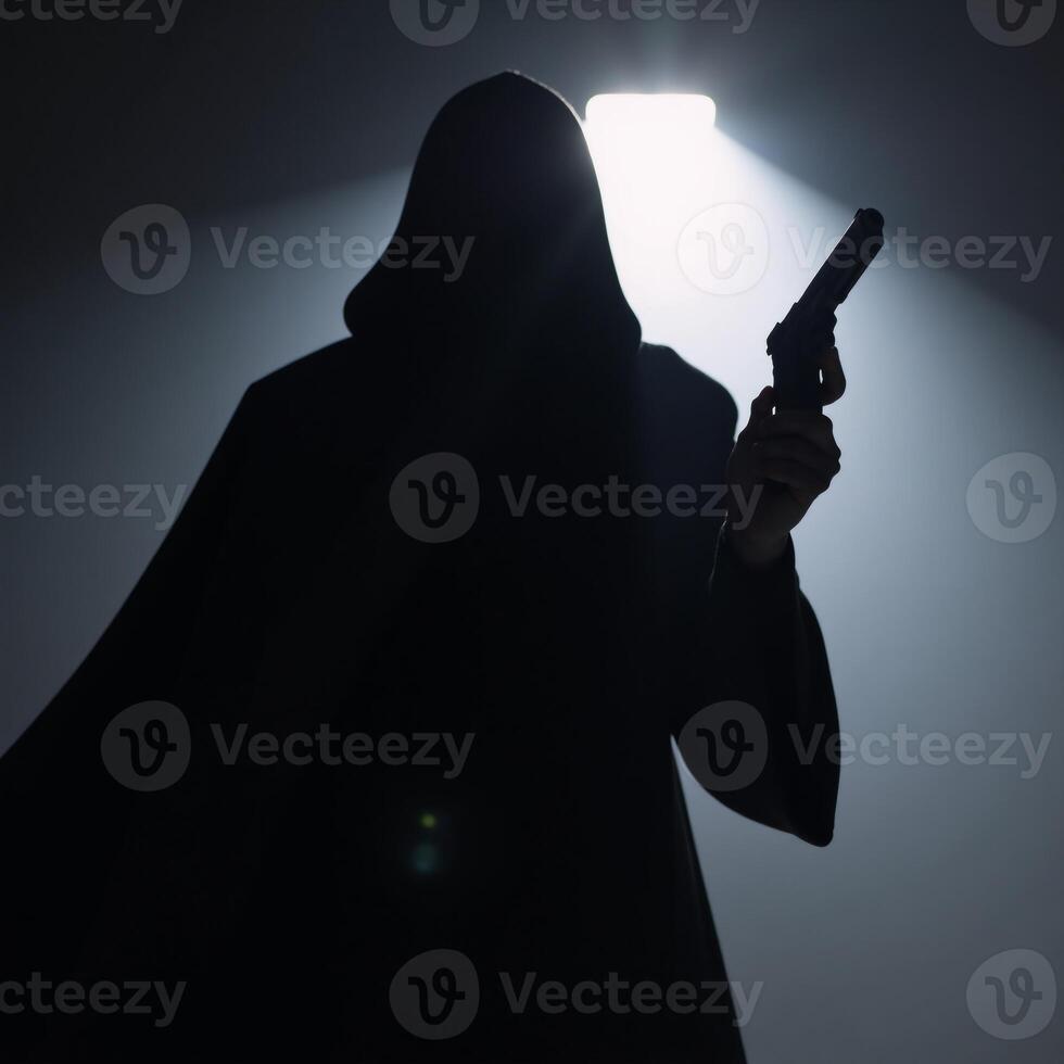 Hooded figure with gun in dark silhouette photo