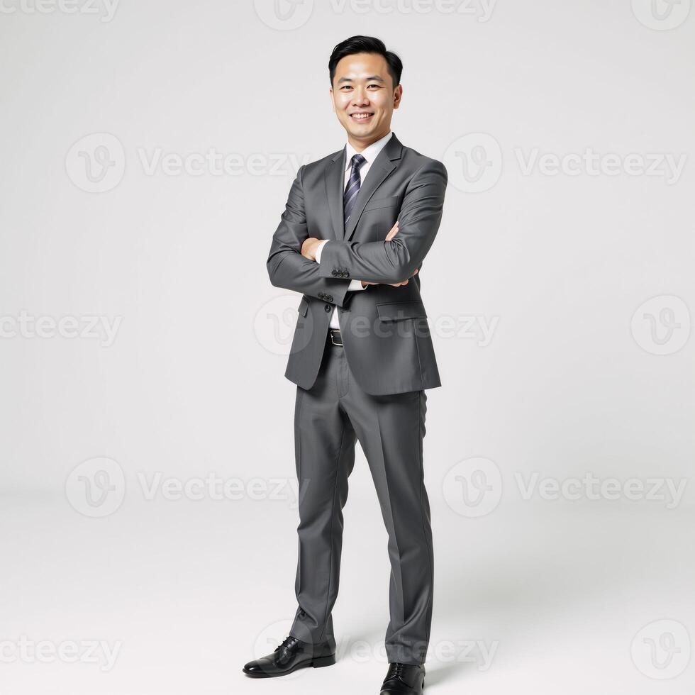 Portrait of an Asian businessman in a grey suit exuding confidence and friendliness against a purewhite backdrop photo
