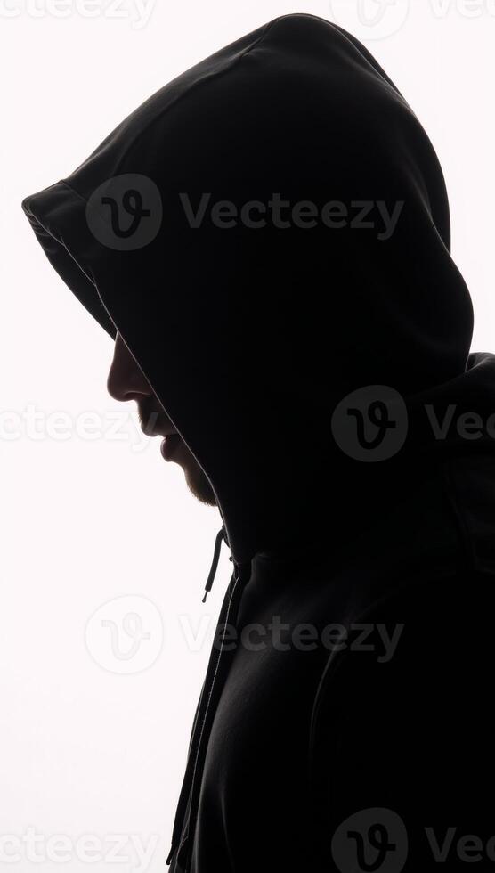 Dark isolated portrait of a hooded hacker in a black silhouette against a stark white backdrop photo