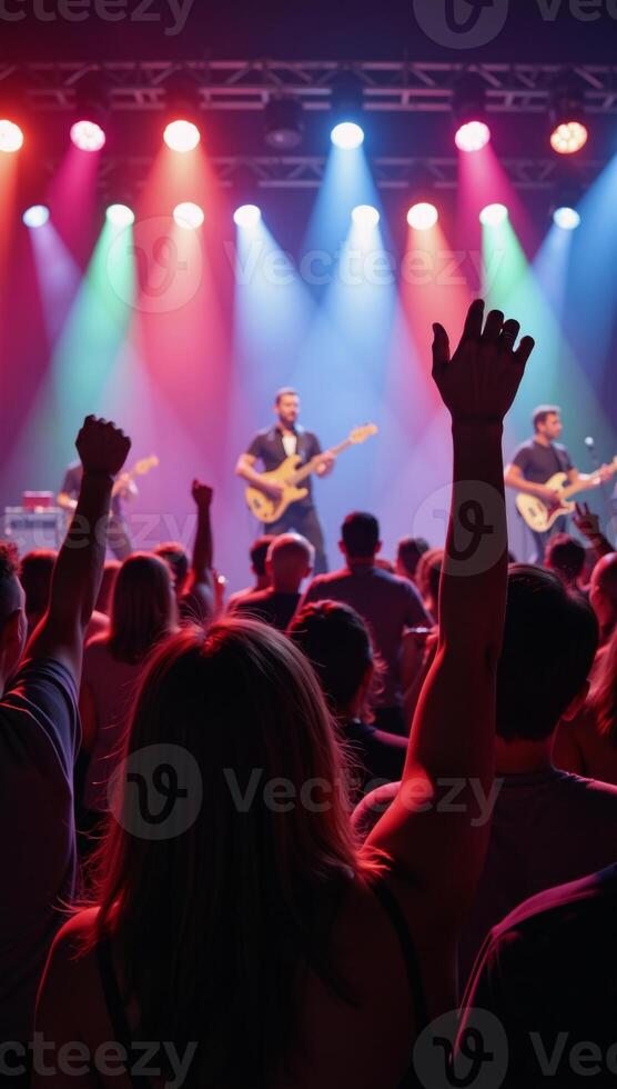 Vibrant concert atmosphere featuring a crowd waving their arms while a band plays live music under stage lighting photo