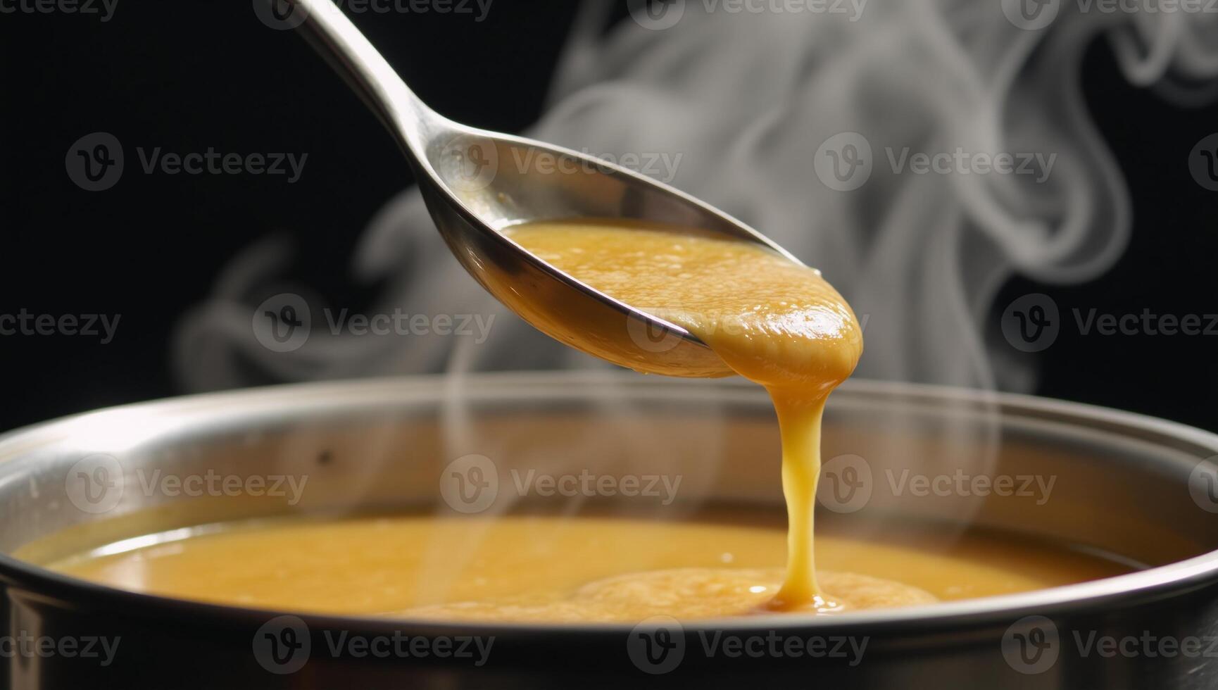 A ladle pours hot soup into a large pot photo