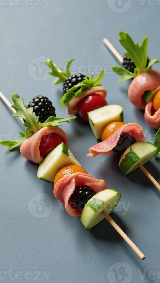 Bitesized prosciutto blackberry cucumber arugula skewer on a grey backdrop photo
