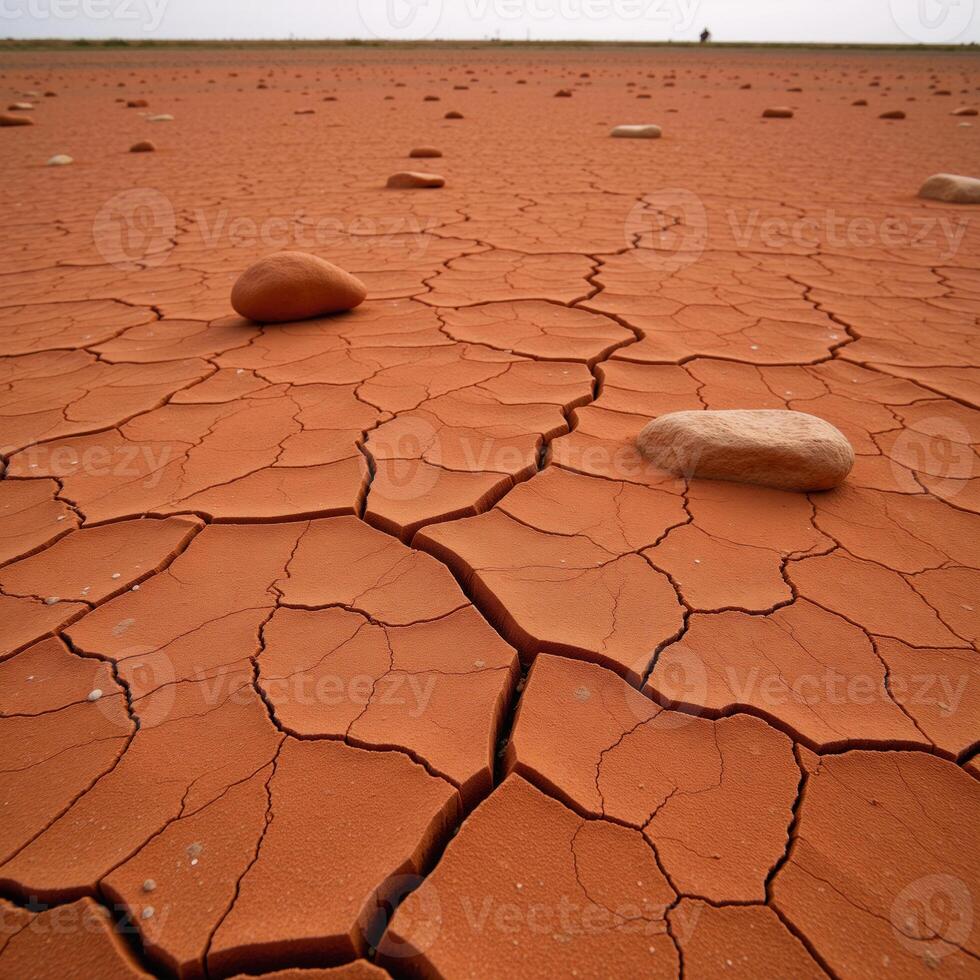 Craggy weathered landscape featuring cracked red soil and strewn rocks photo