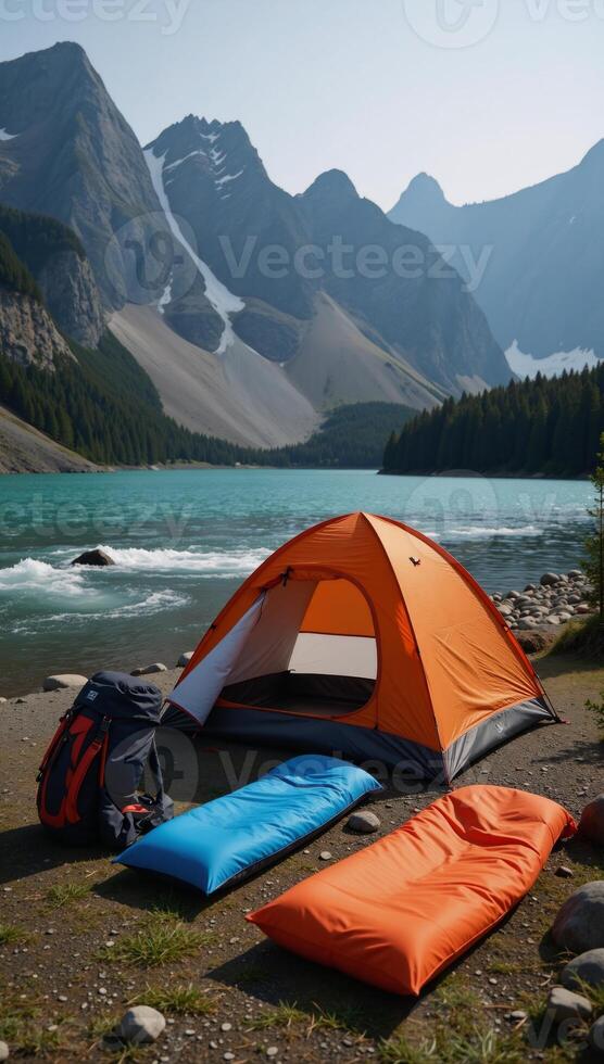 A tent pitched beside a mountain river within scenic lakeside mountain terrain photo