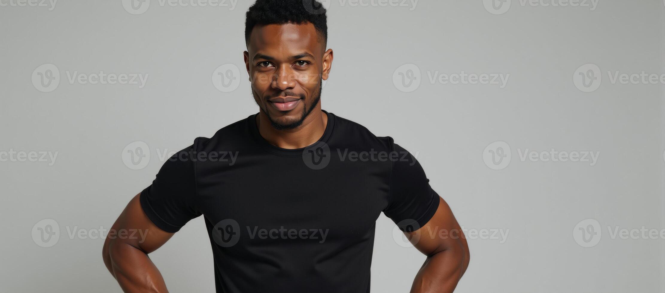 A confident AfricanAmerican model showcases the flexibility of a fitted black tee on a neutral backdrop photo