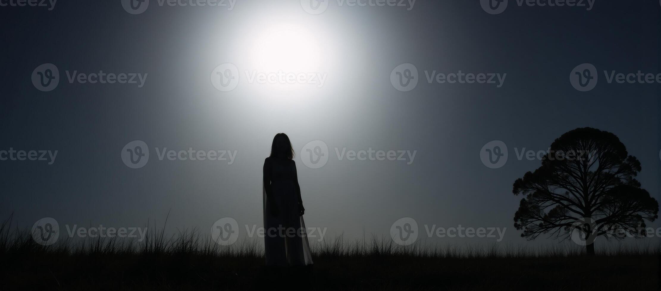 Ghostly figure depicted as silhouette against a lit night sky with a full moon over an open field photo