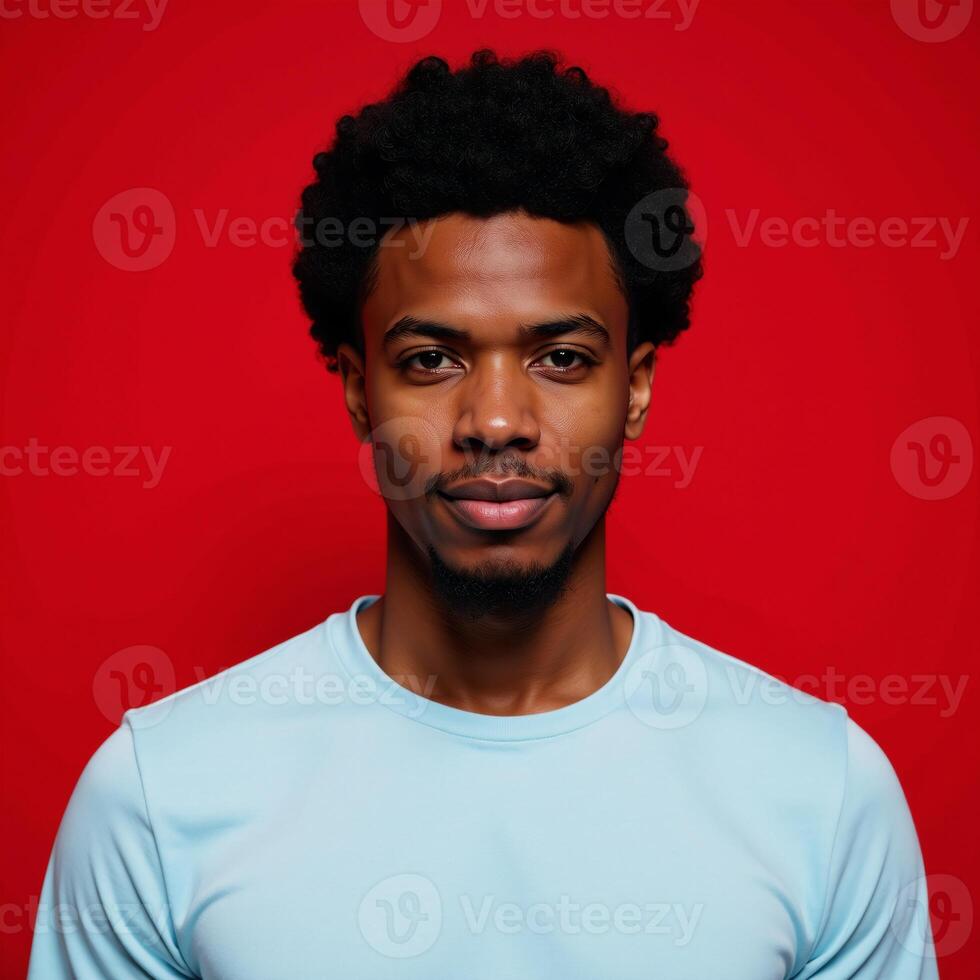 An African American man with an Afro stands against a red backdrop photo