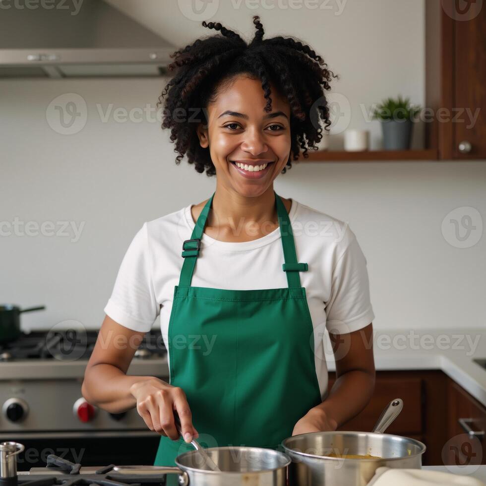 A smiling happy AfricanAmerican woman cooking in green apron stock image photo