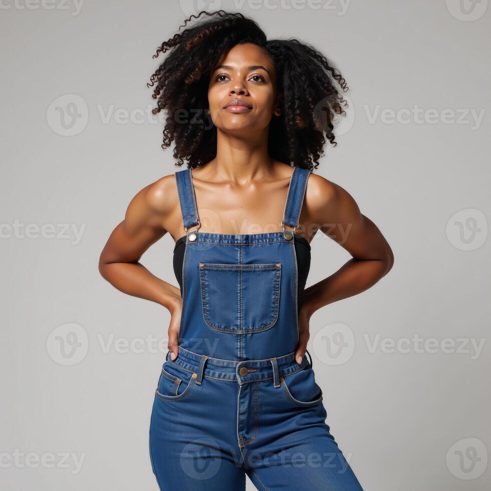 A confident AfricanAmerican woman with an Afro sports denim overalls while gazing upward photo