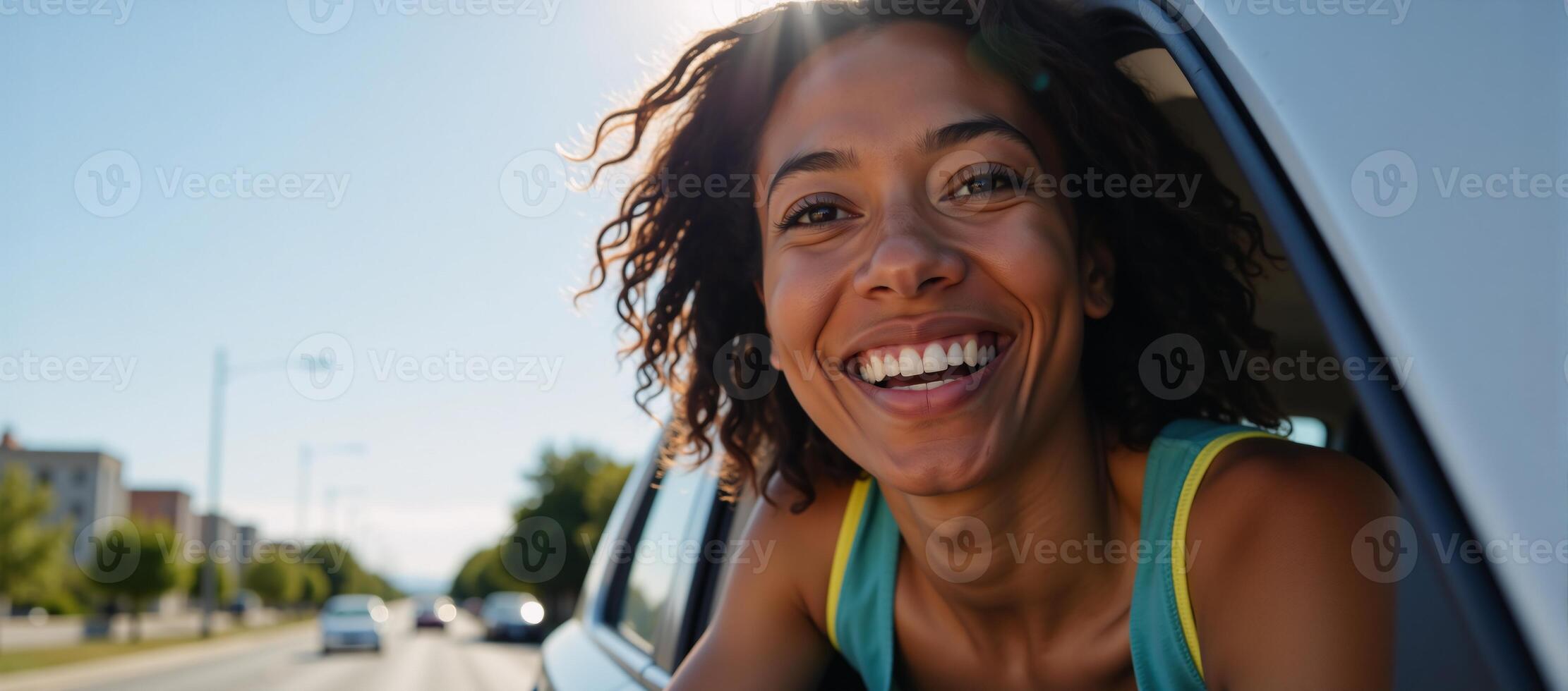 A joyous Black woman enjoys sunlight from her moving car window photo