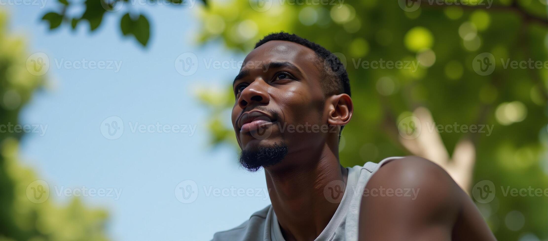 An introspective AfricanAmerican collegian contemplates under a clear sky photo