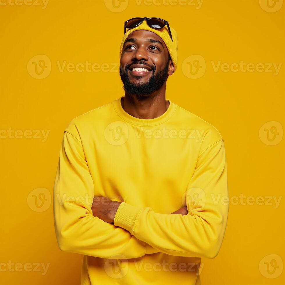 Optimistic Black Man in yellow beanie sweatshirt points upward against bright yellow backdrop Advertising wallpaper mockup featuring African American male photo