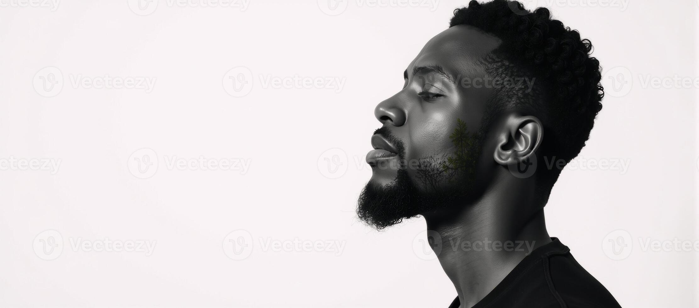A blackandwhite double exposure portrait showcases a serene African American man sitting within a forest backdrop against a stark white background his closed eyes convey an air of contemplative peace photo