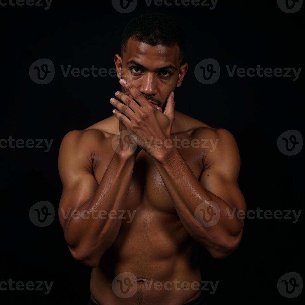 Muscular African American boxer looks intensely into the camera with a covered head on a black background sweaty photo