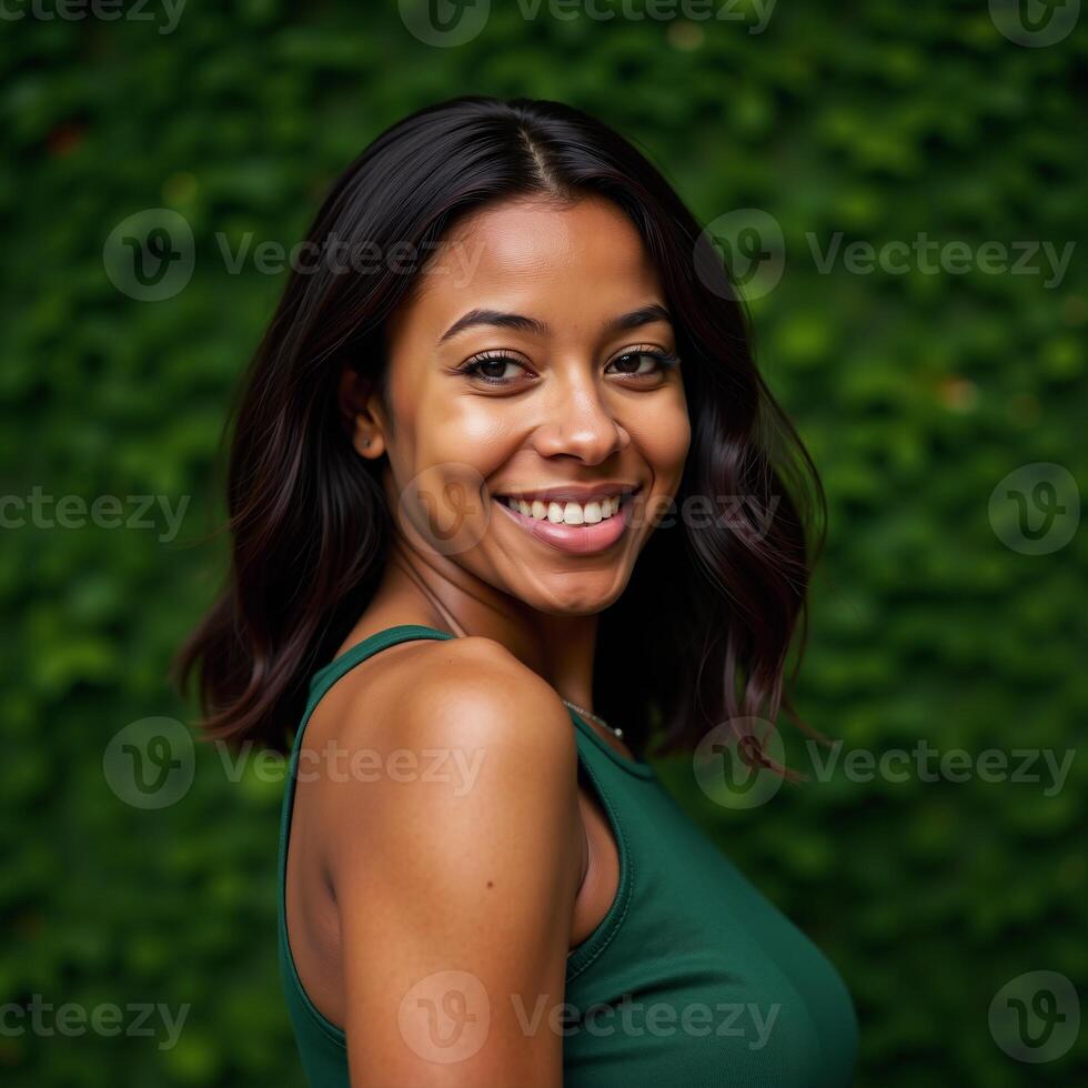 A closeup portrait showcases an African American woman with a smile dressed in a green shirt against a matching backdrop photo
