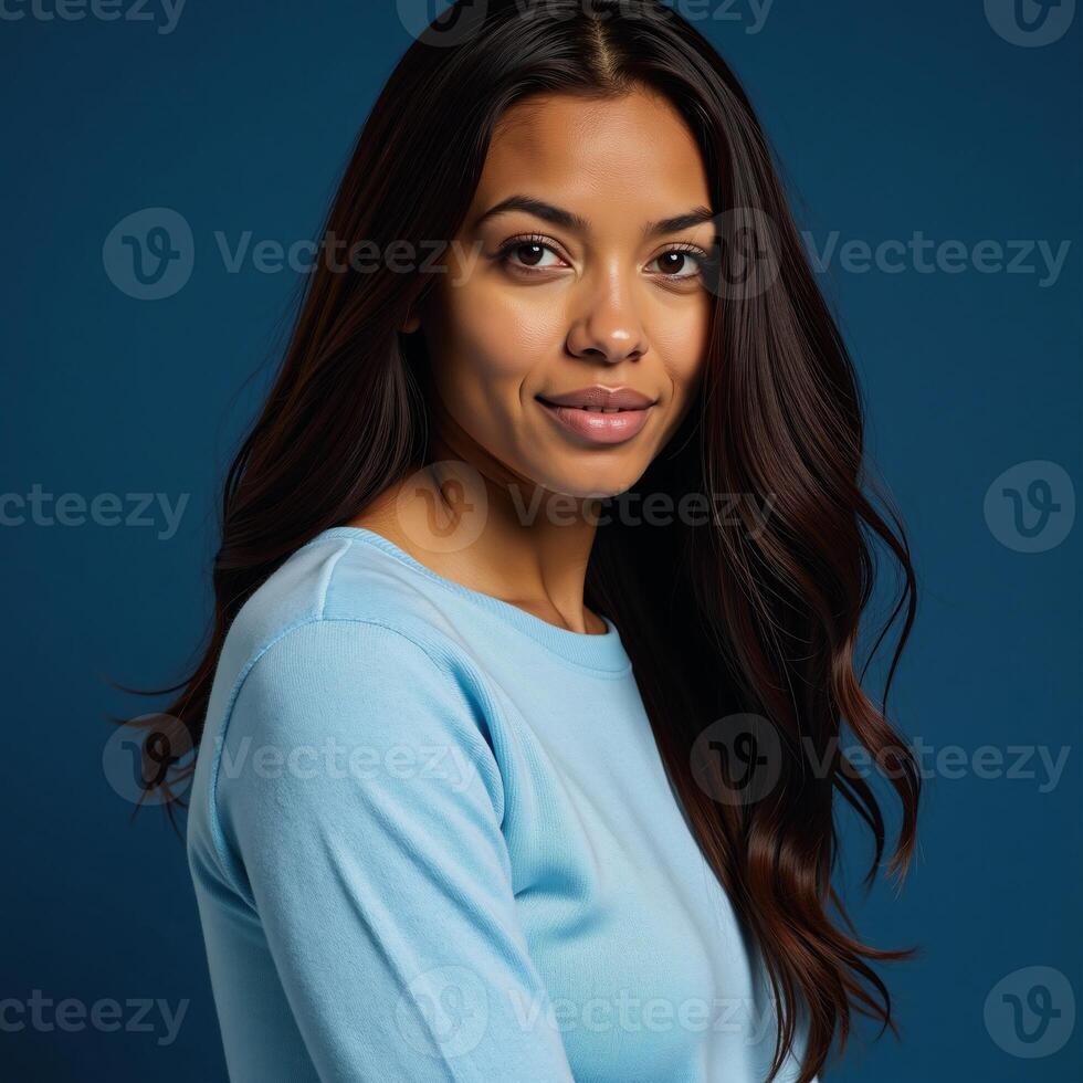 AfricanAmerican woman in light blue sweater posed against blue backdrop long wavy hair striking blue eyes photo