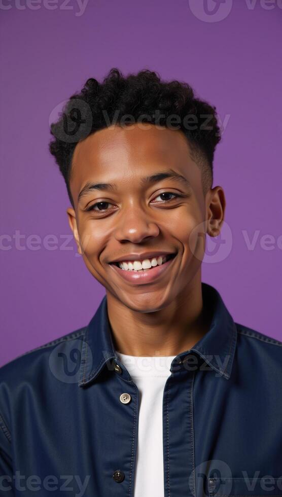 A confident African American teen boy exudes joy and style while beaming brightly against a vibrant purple studio backdrop symbolizing educational empowerment and youthful energy photo