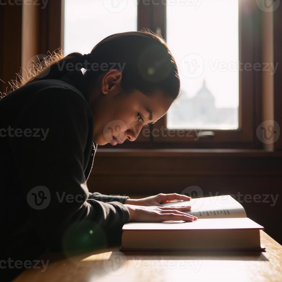 A sunlit college library scene Closeup of deep concentration on an African American student with a book seated in a cozy corner photo