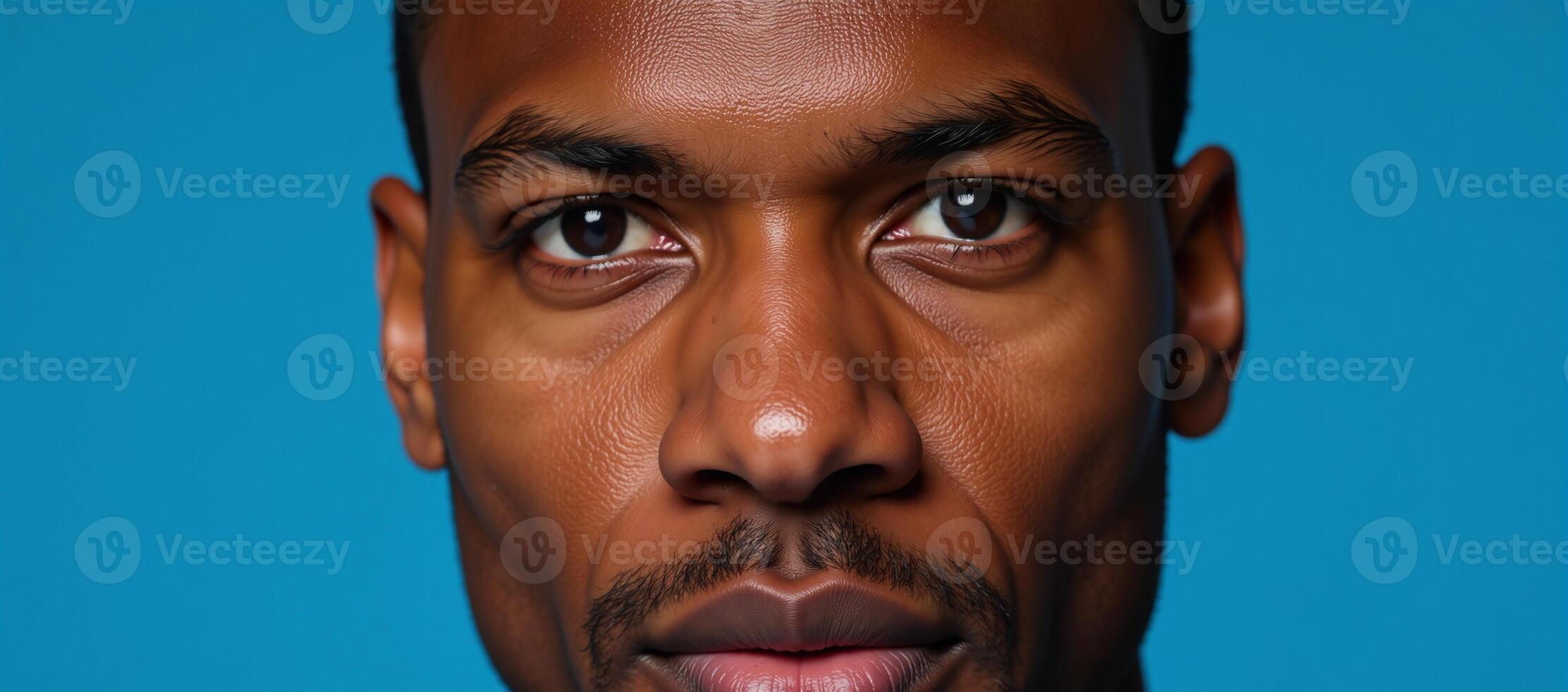 Closeup portrait featuring an African American man against a blue backdrop with emphasis on his expressive eyes photo