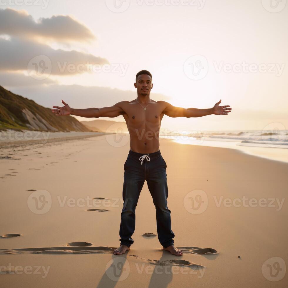 A young African American male stands confidently with arms outstretched on a sunny beach setting photo