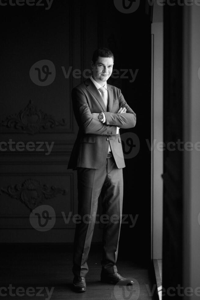 portrait of groom in blue three piece suit with tie on wedding day photo