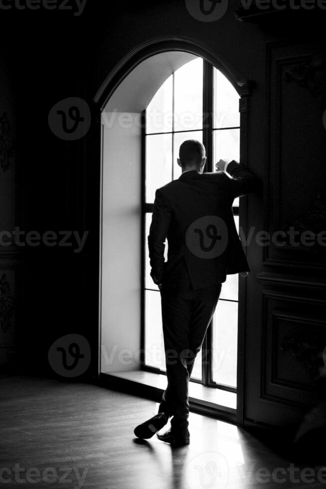 portrait of groom in blue three piece suit with tie on wedding day photo