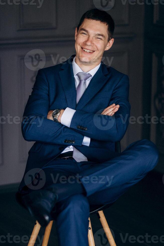 portrait of groom in blue three piece suit with tie on wedding day photo