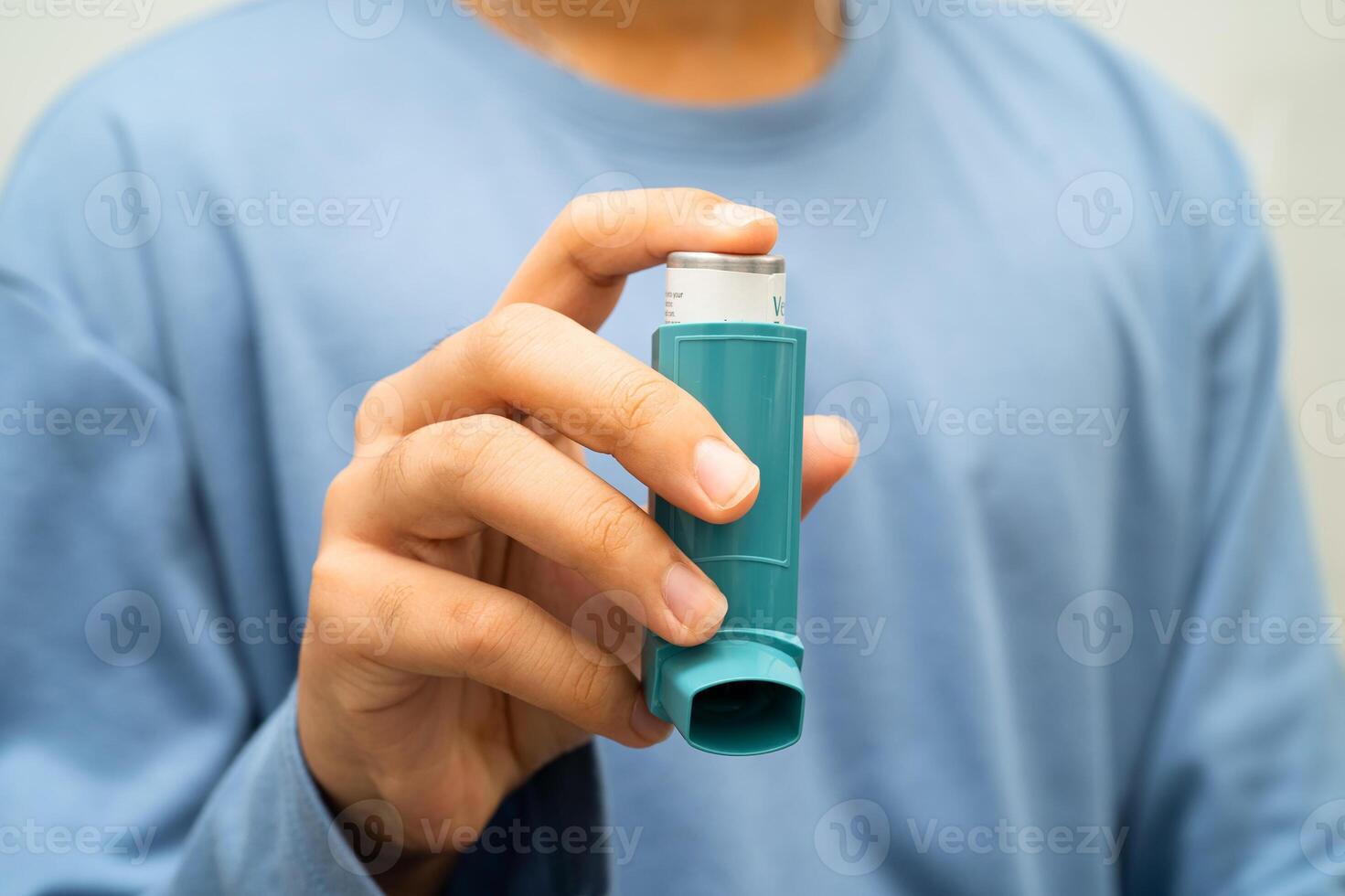 Asthma and chronic obstructive pulmonary disease COPD, Asian young man using metered dose inhaler MDI. photo