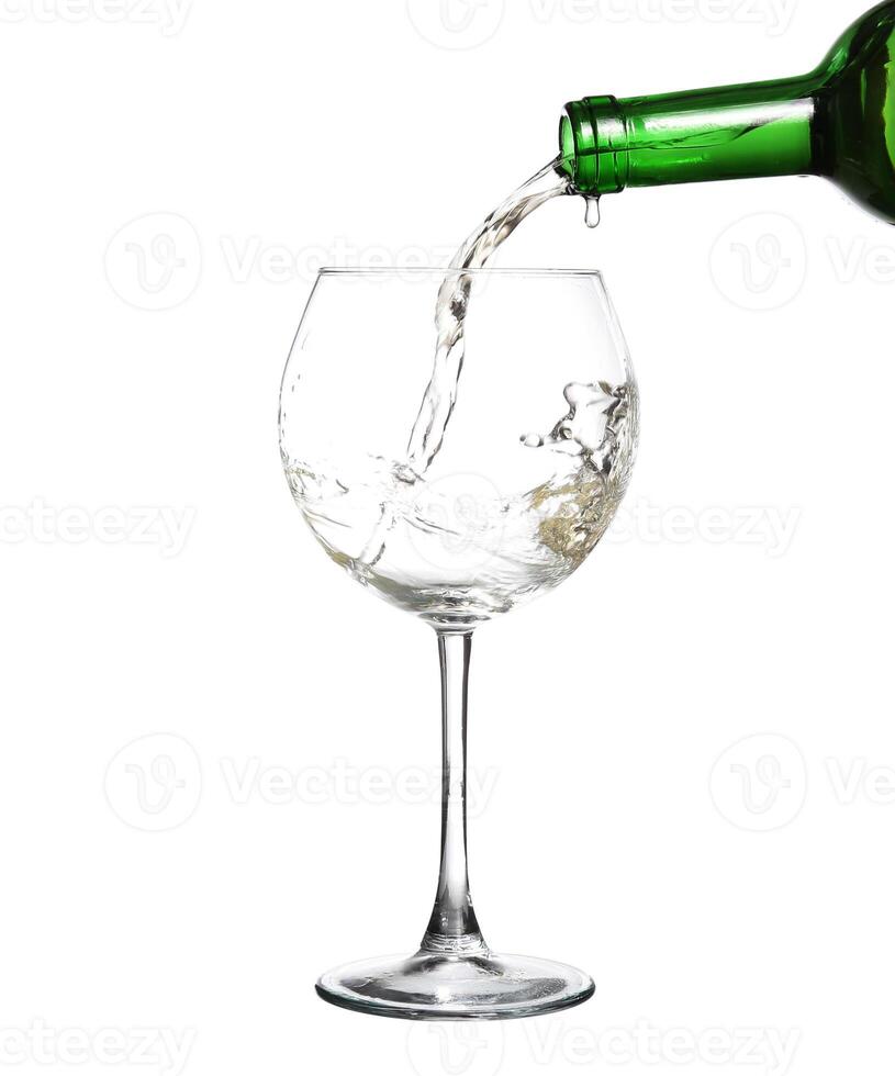 White wine pouring from the bottle intro the glass on white background photo
