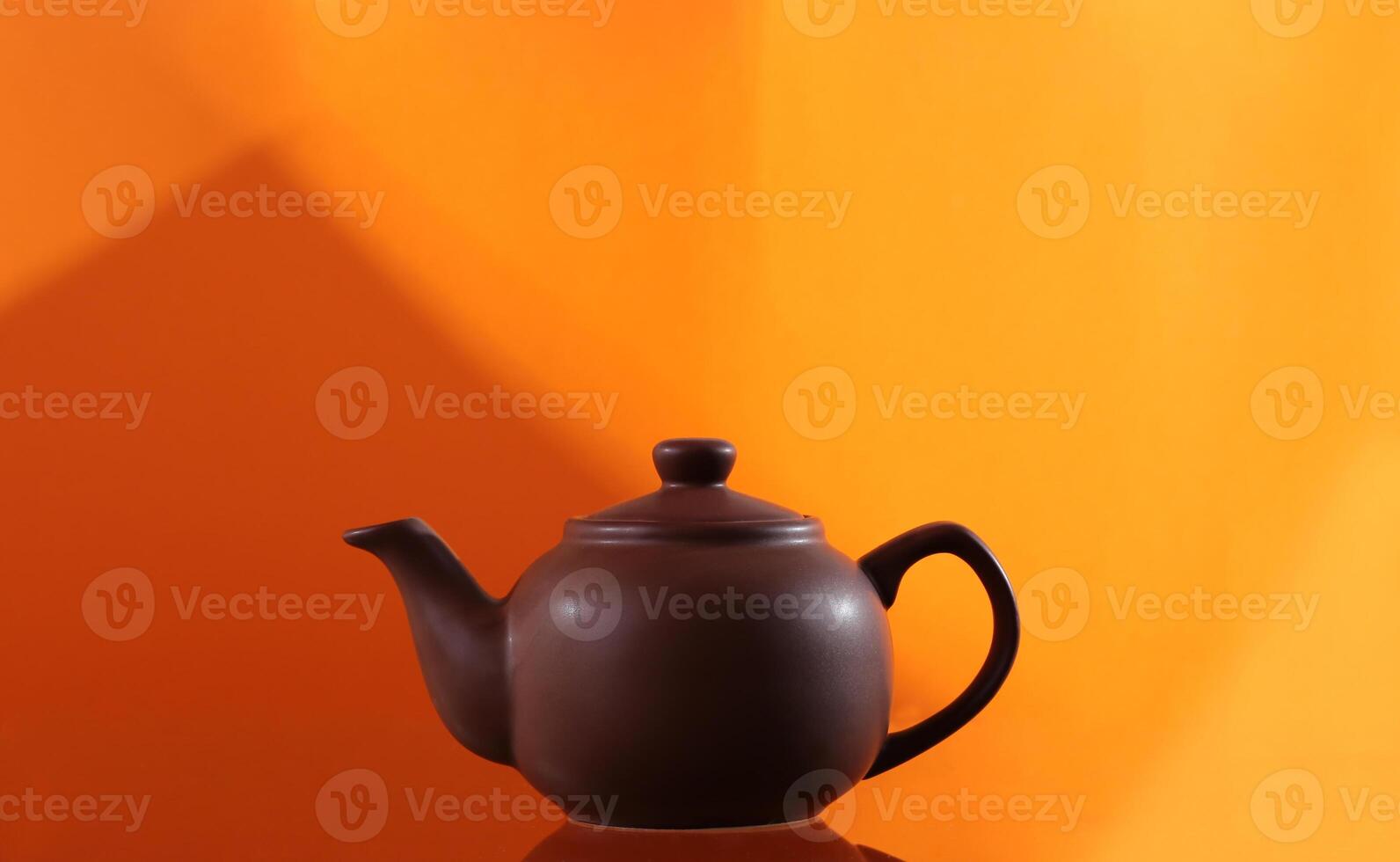 teapot from clay on an orange background with geometric pattern photo