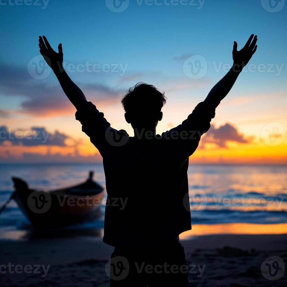 A man is standing on the beach with his arms raised photo