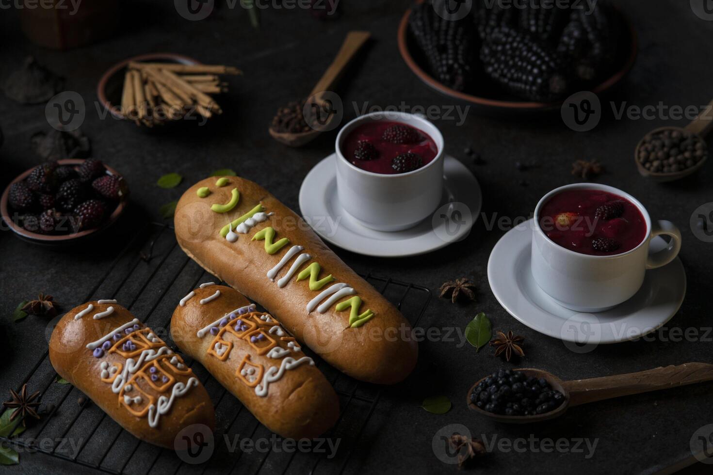 Guaguas de Pan with cups of Colada Morada, traditional Ecuadorian food for the day of the dead, surrounded by the ingredients to cook the colada photo
