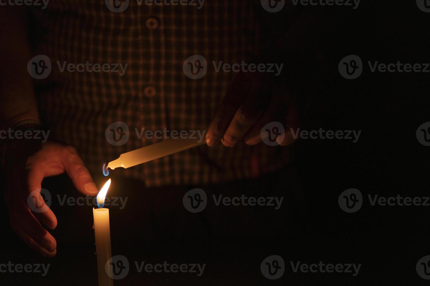 Close up of man's hand lighting a candle in the dark photo